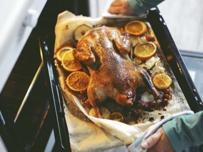 frau-die-ente-mit-gemuse-kocht-und-es-vom-ofen-setzt